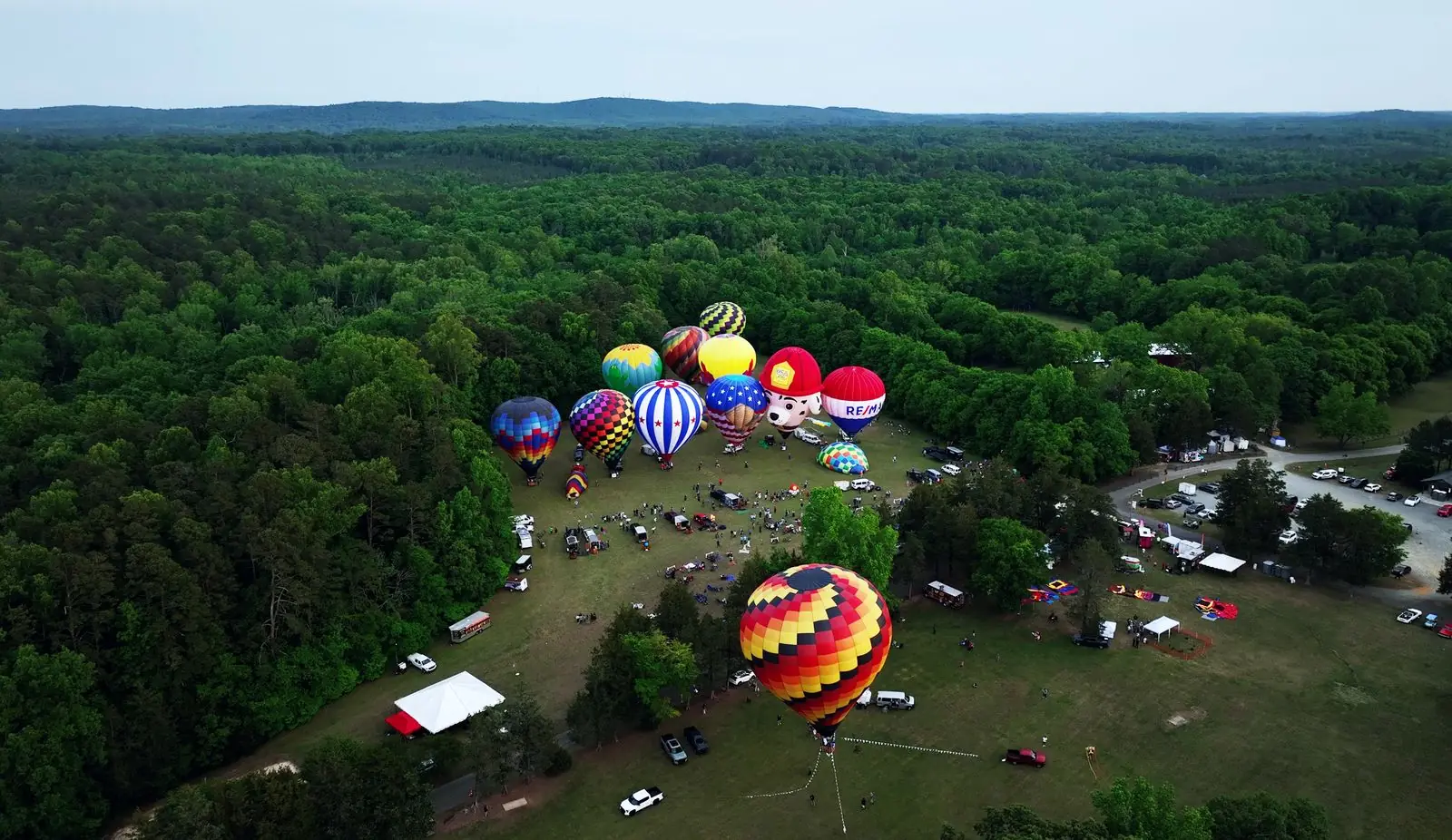 Hot air balloons inflating at the Alcovets Balloon Festival at Cedarock Park in Burlington, seen from above